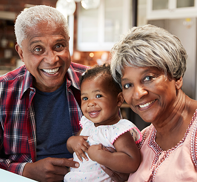 Grandparents and grand daughter smiling at the camera.